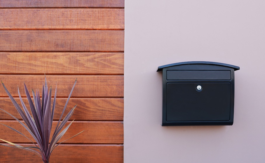 Black locking wall mount mailbox mounted on a wall