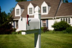 white aluminum mailbox with flag raised installed in front of a home