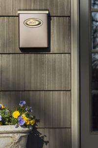 Decorative bronze wall mounted mailbox on a house