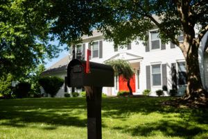 Black heavy-duty mailbox in front of home with bright red door