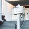 Side view of white post mount mailbox with decorative background