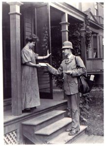 Old photo of post man handing mail to women