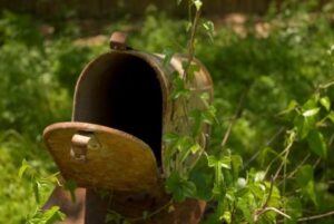 Rusty brown mailbox next to trees