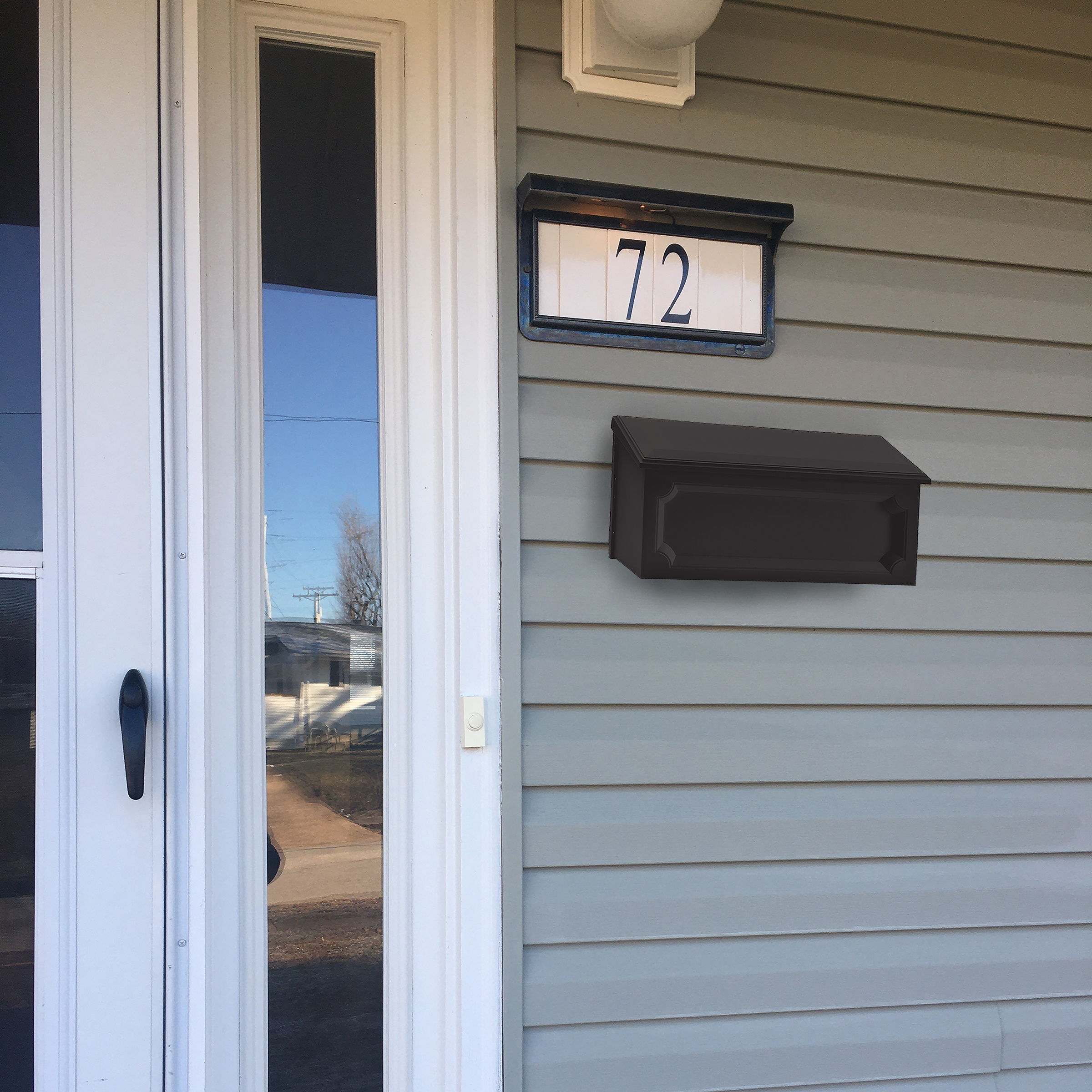 Front entrance of a house: glass-paneled white door, light gray siding, and a mailbox with the number 72 beside it.