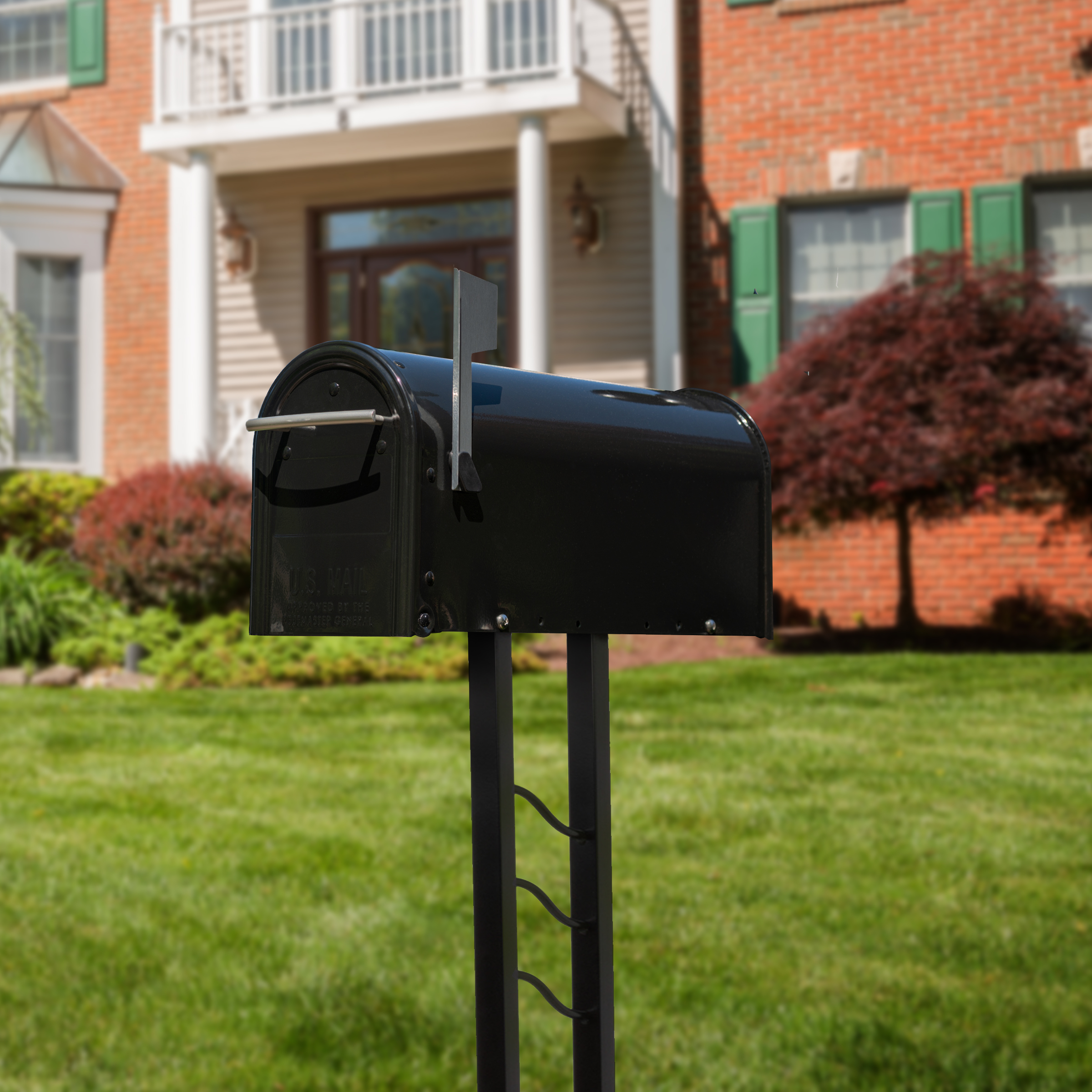 Black mailbox on a metal post in a suburban front yard with a brick house and green lawn in the background.