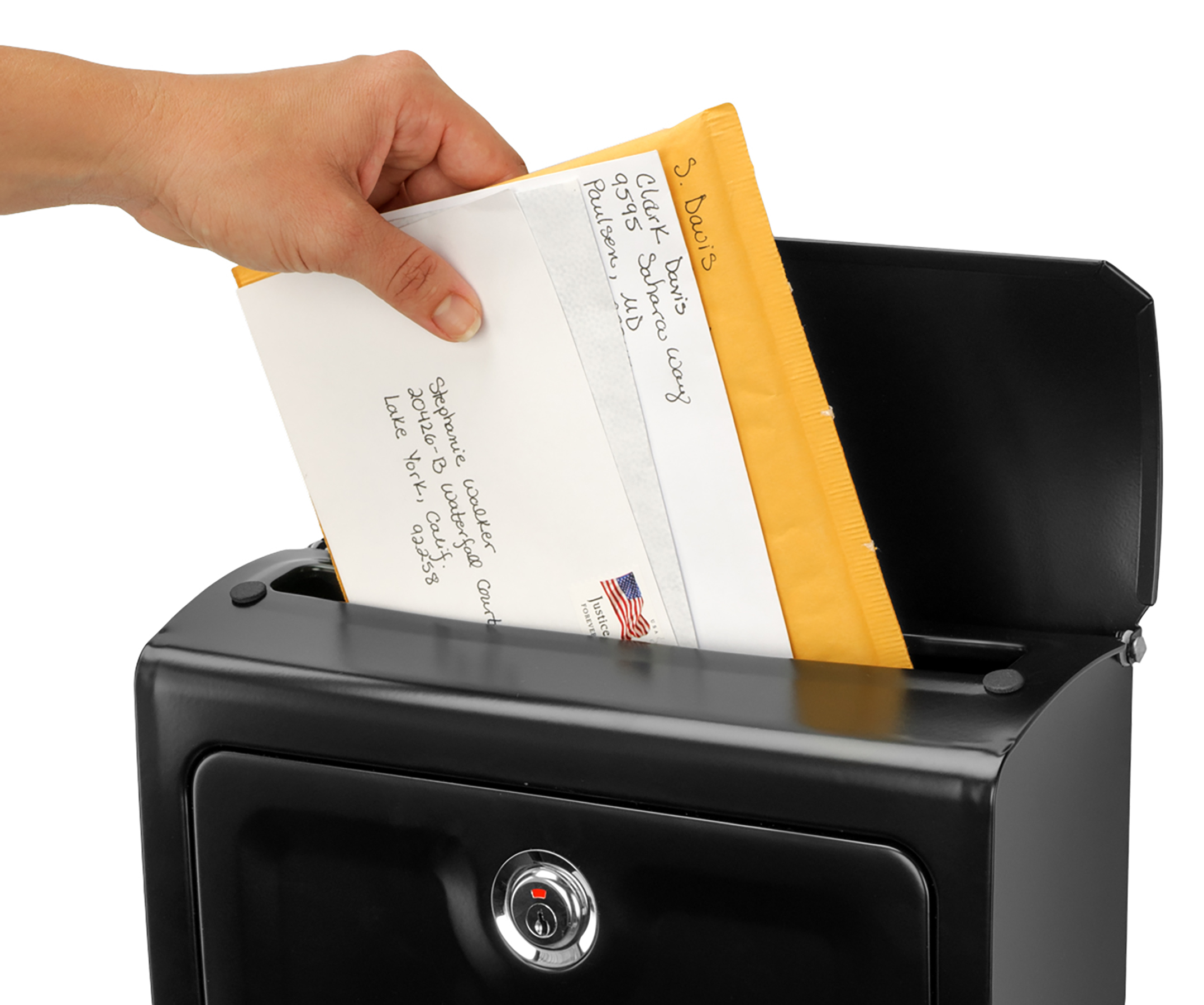 Hand placing a white letter into a yellow padded envelope and dropping it into a black secure deposit box with a lock exposing the slot.