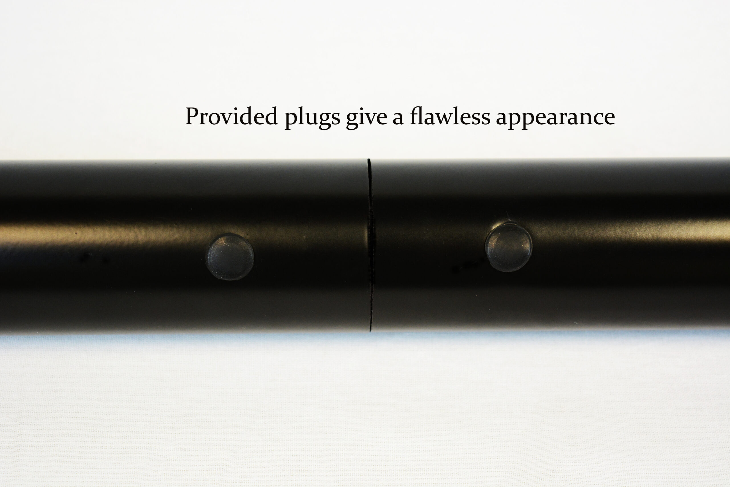 Close-up of a black cylindrical tube with two round plugs and a vertical seam; caption reads, 'Provided plugs give a flawless appearance'.