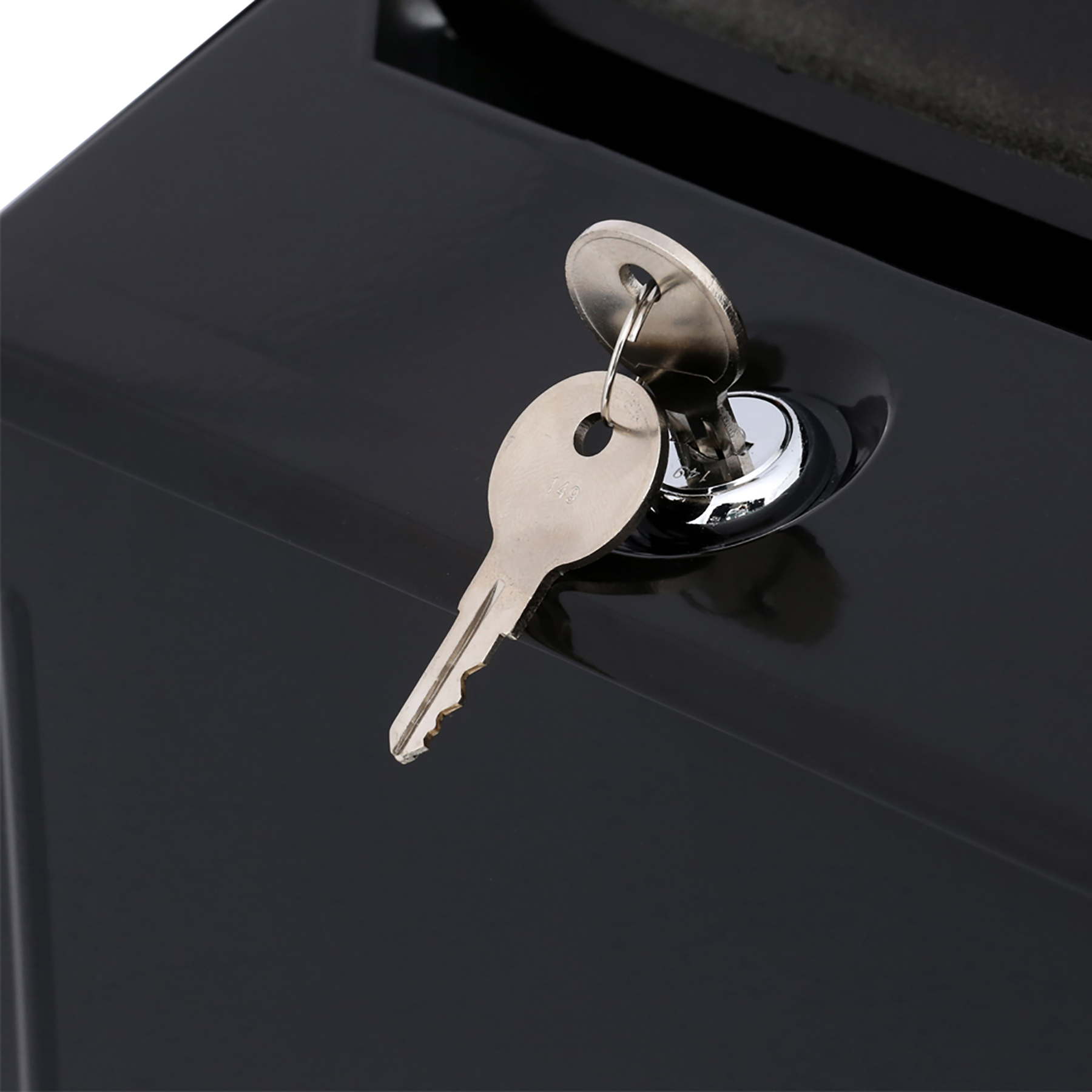 Key resting in a shiny lock on a dark, glossy surface (likely a safe or cabinet).