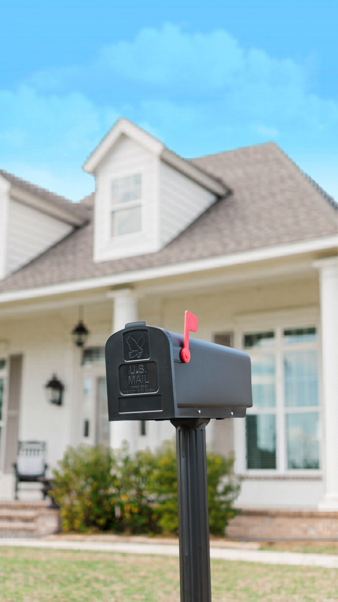 Black US Mail mailbox with the red flag raised in a suburban front yard.