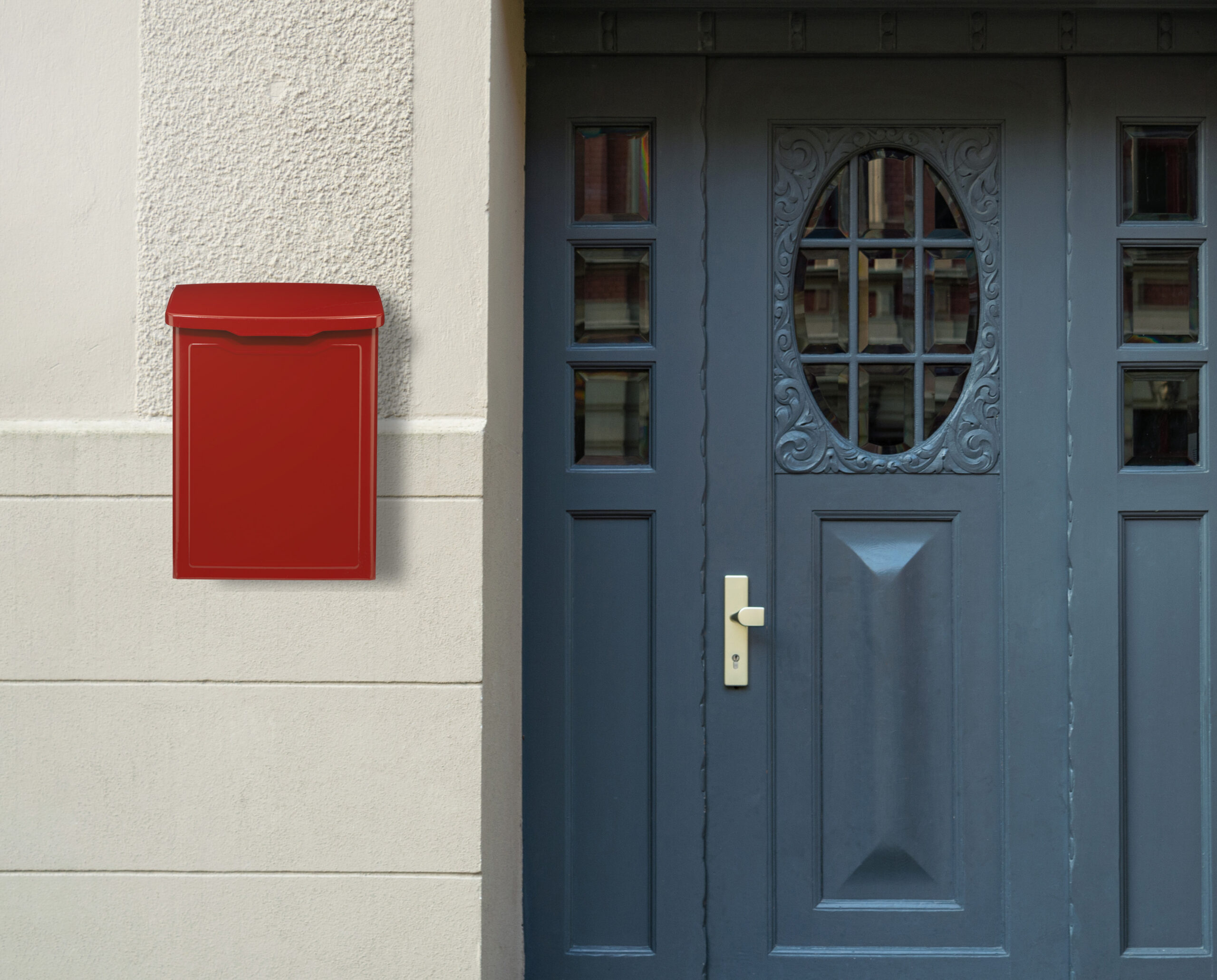 Red wall mailbox mounted next to a dark blue ornate front door on a light stucco wall.
