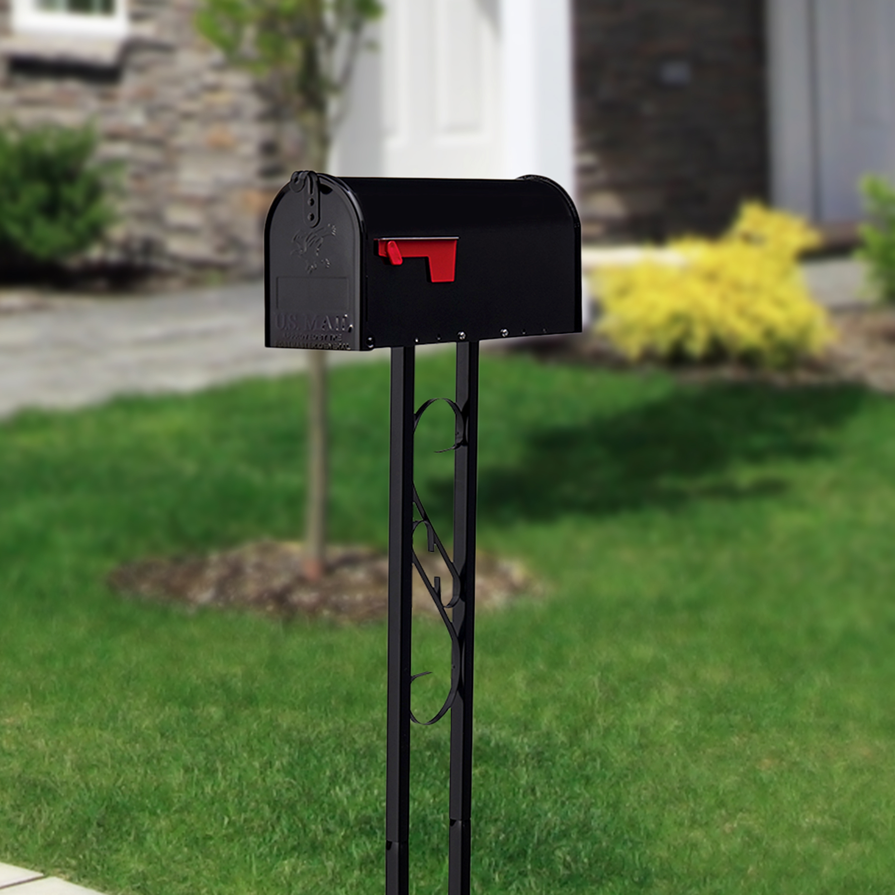 Black curbside mailbox with a red flag raised on a decorative black iron post in a front-yard setting.