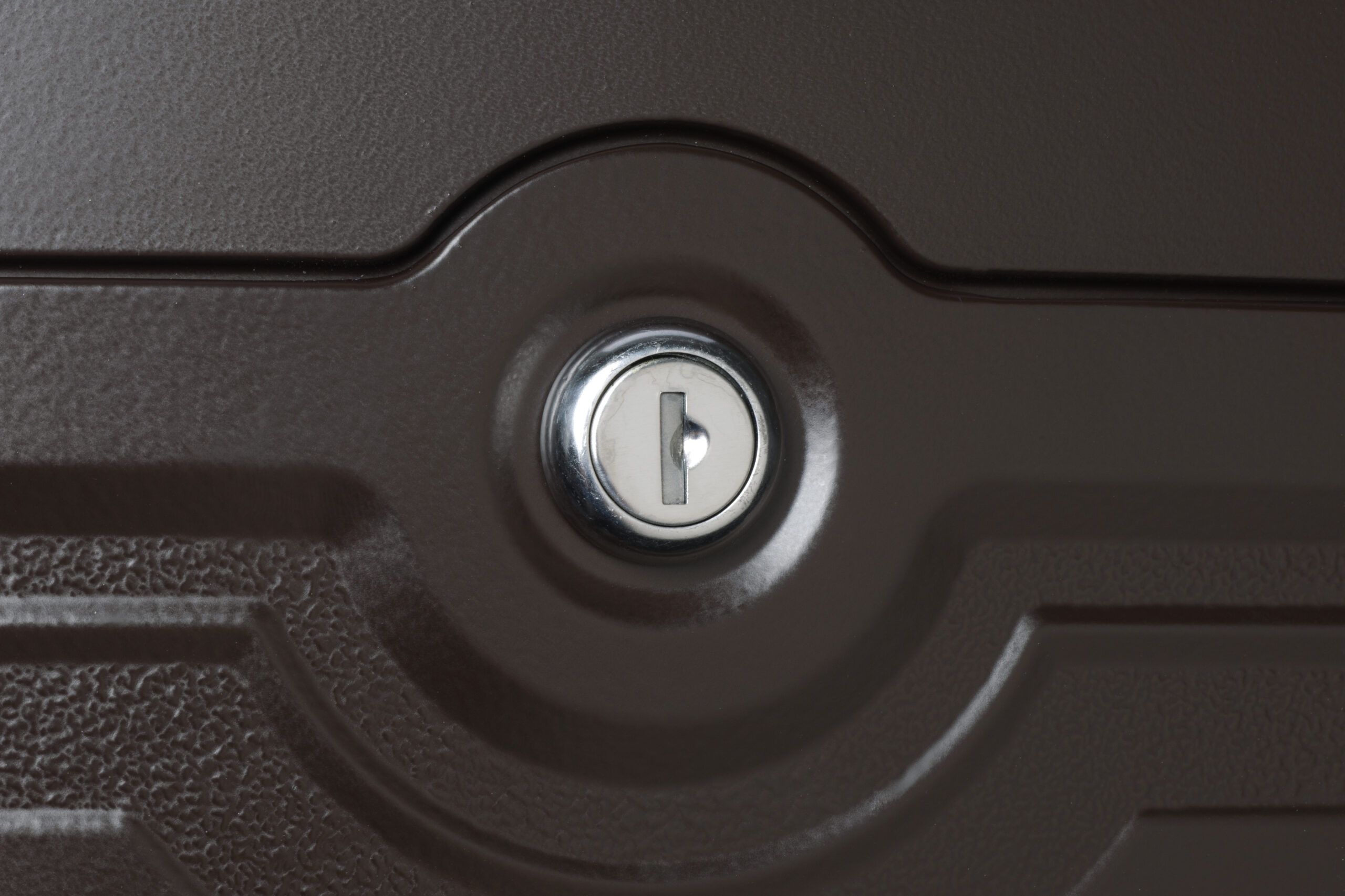 Close-up of a round keyhole in a brown metal door with a silver rim.
