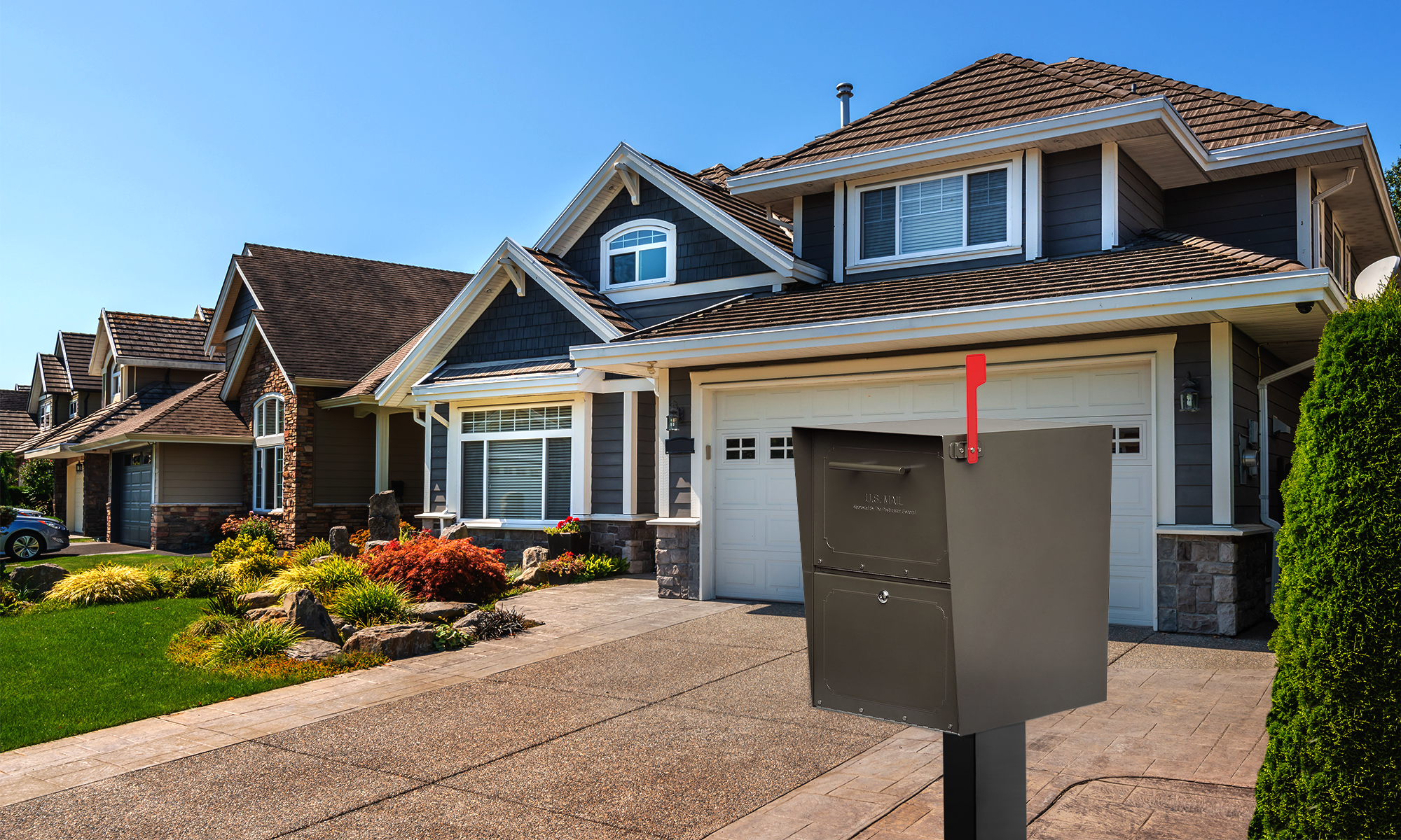 Row of suburban houses with manicured yards; a gray mailbox on a post with a red flag in the driveway foreground.