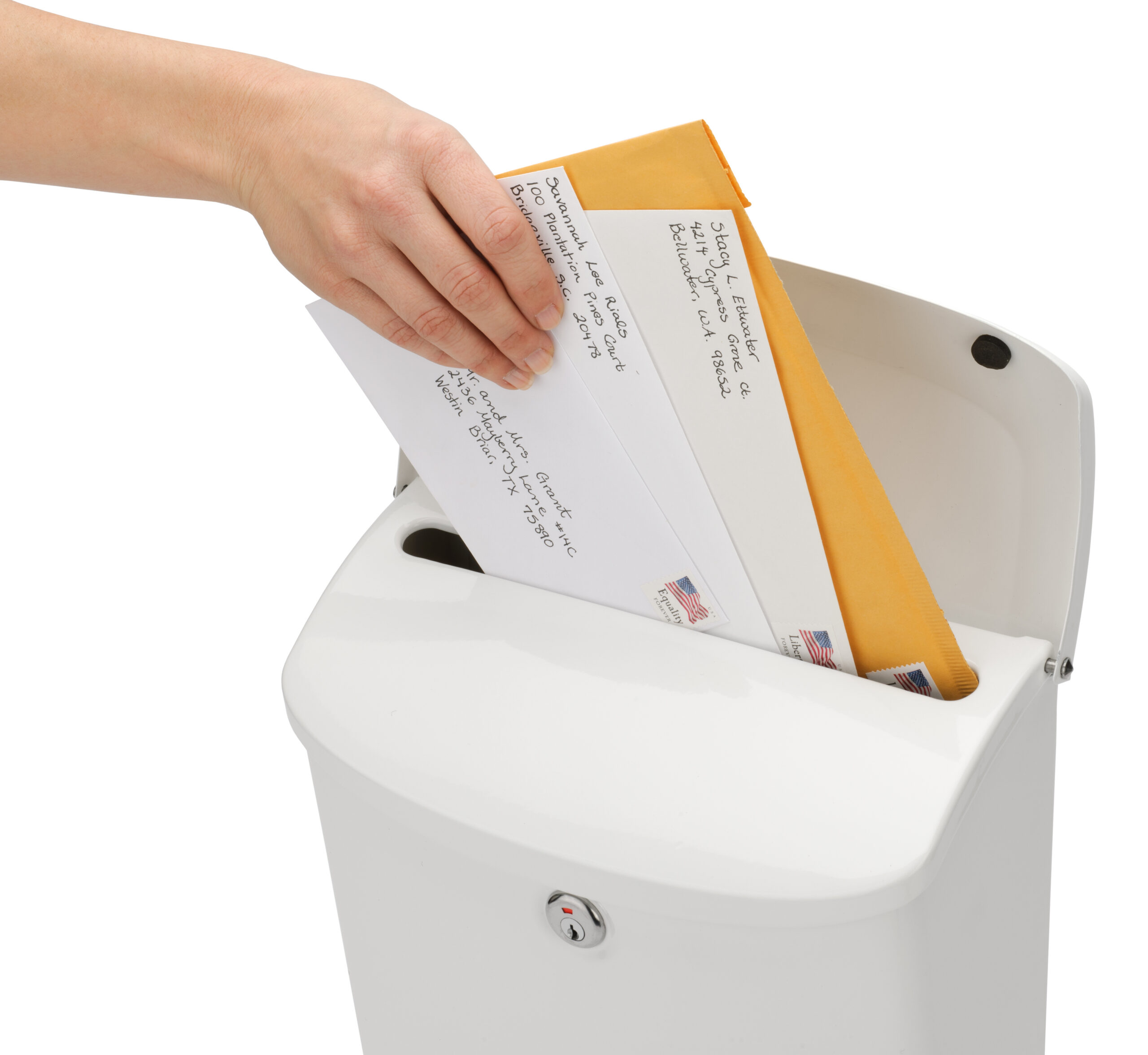 Hand dropping envelopes into a white mailbox with a slot.