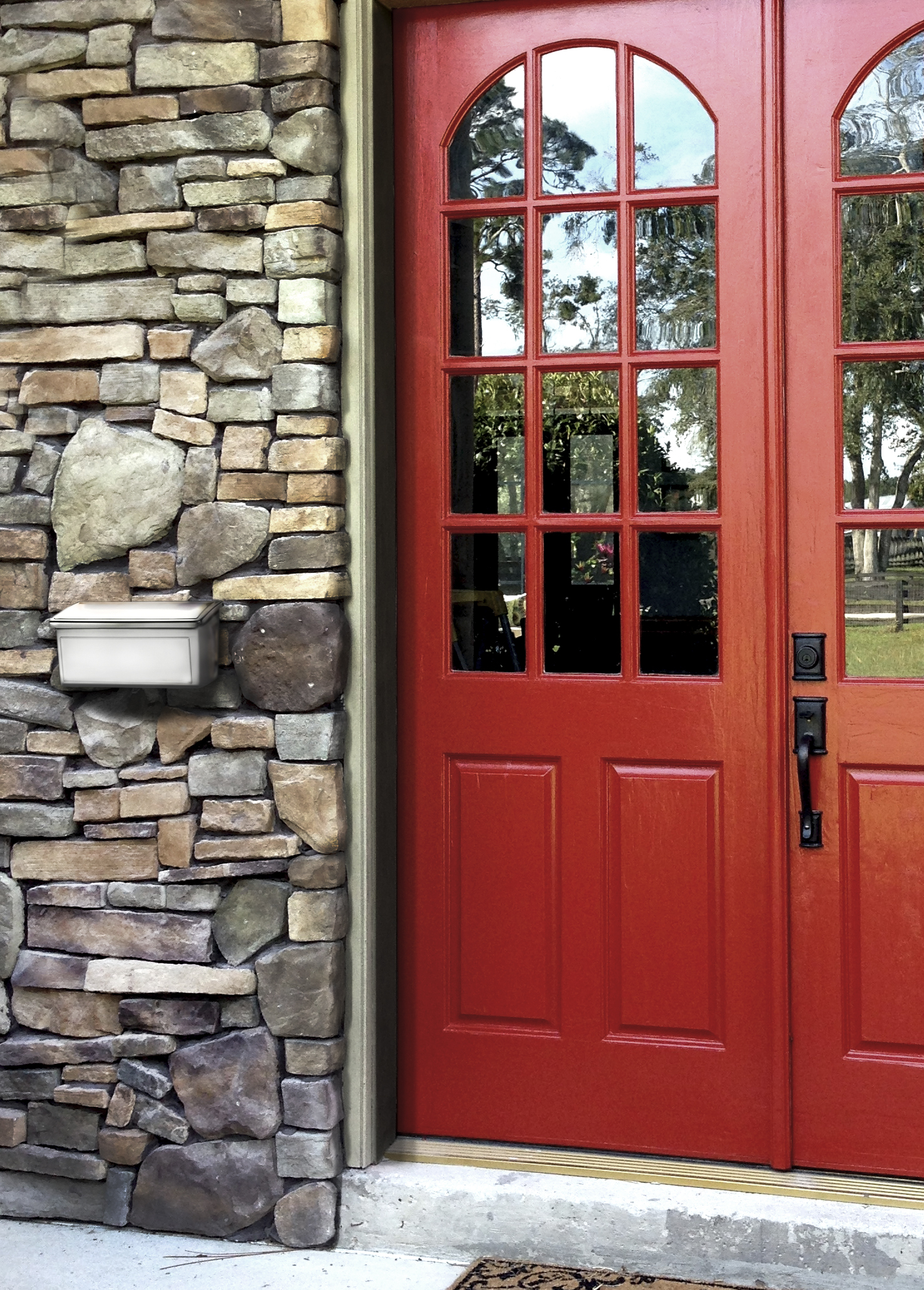 Red double front doors with glass panels set in a stone-entry wall; a mailbox is mounted to the left.