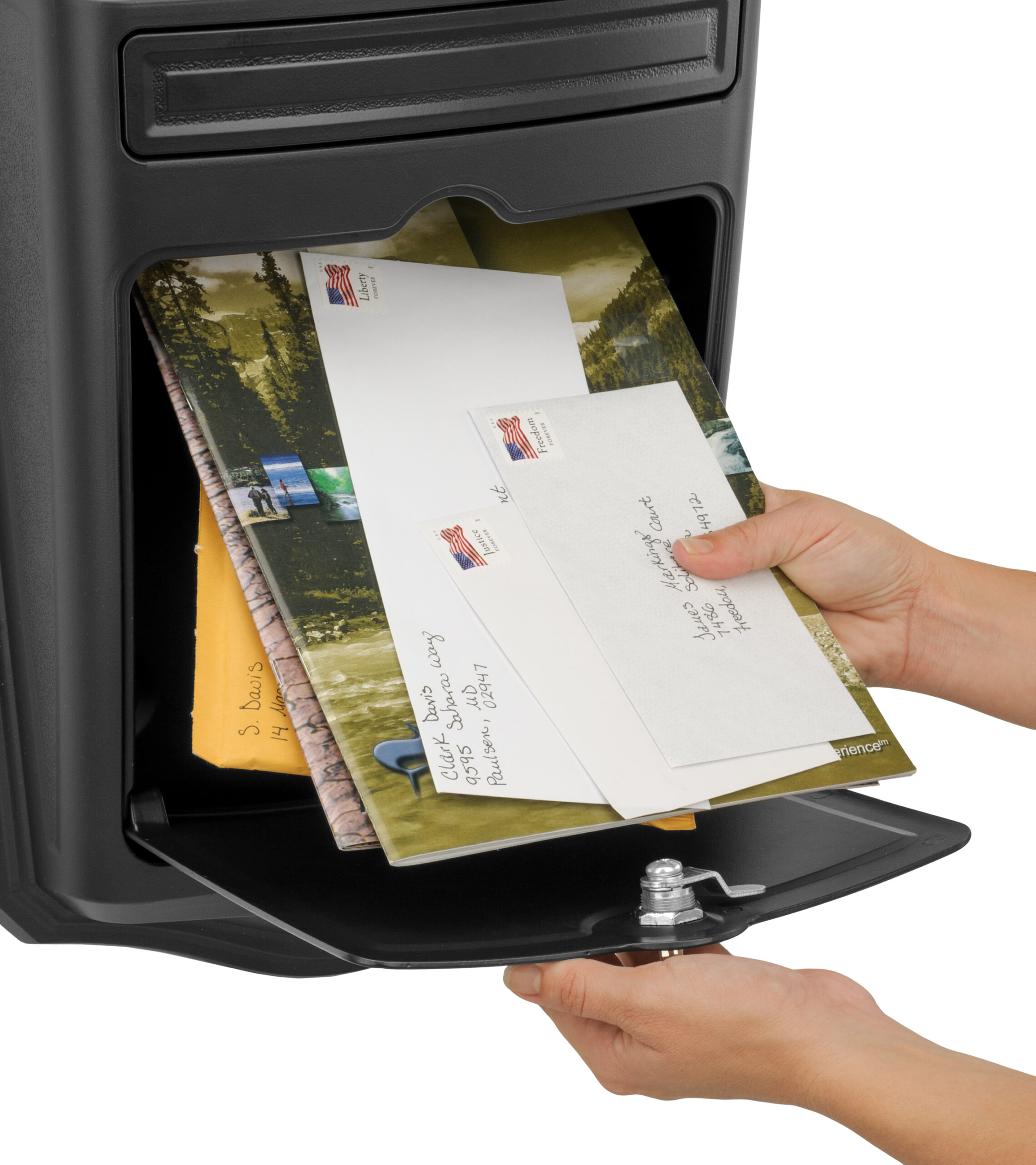 Person placing envelopes into a black exterior mailbox with a open door.