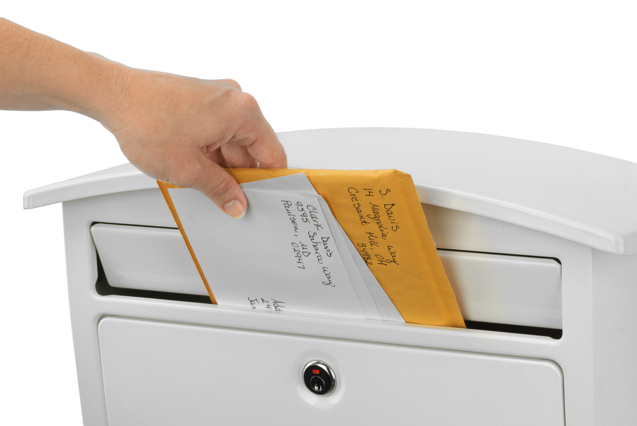 Hand inserting a yellow envelope into a white mailbox slot (front view).