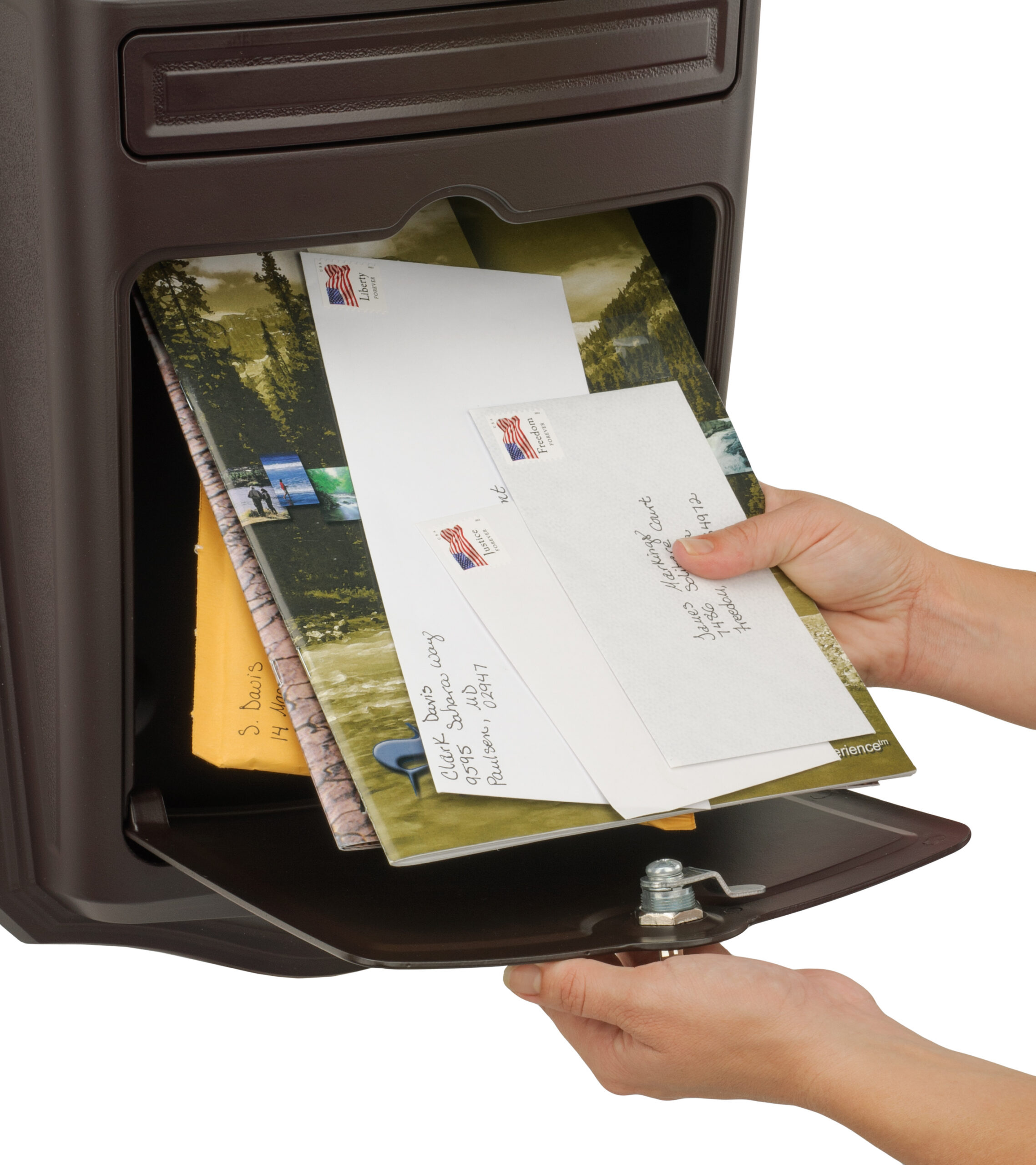 Hand placing white envelopes into an open brown mailbox slot, ready for mailing
