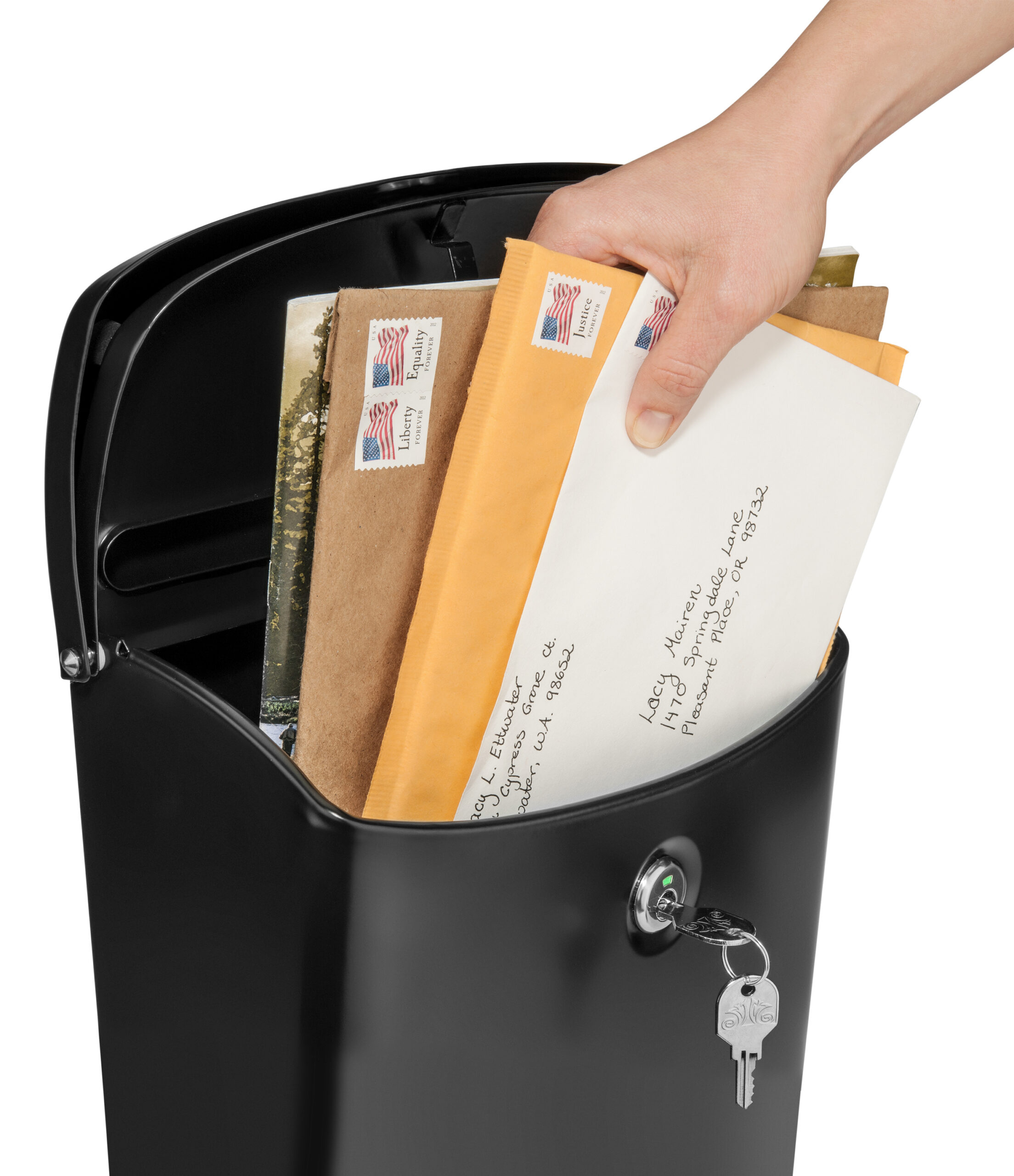 Hand placing several envelopes into a black outdoor mailbox with a key in the lock visible on the front