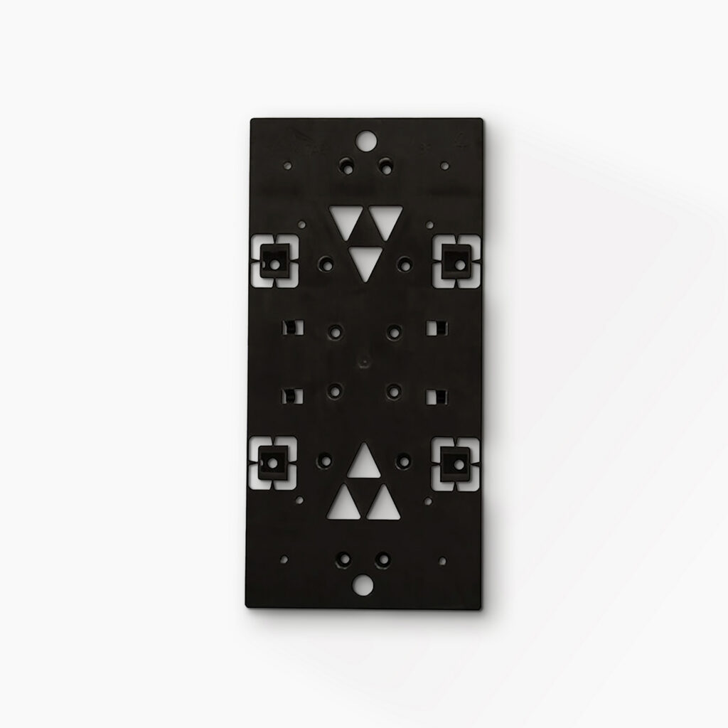 Black rectangular mounting plate with multiple holes and white geometric cutouts (triangles and squares) for hardware alignment or wiring.