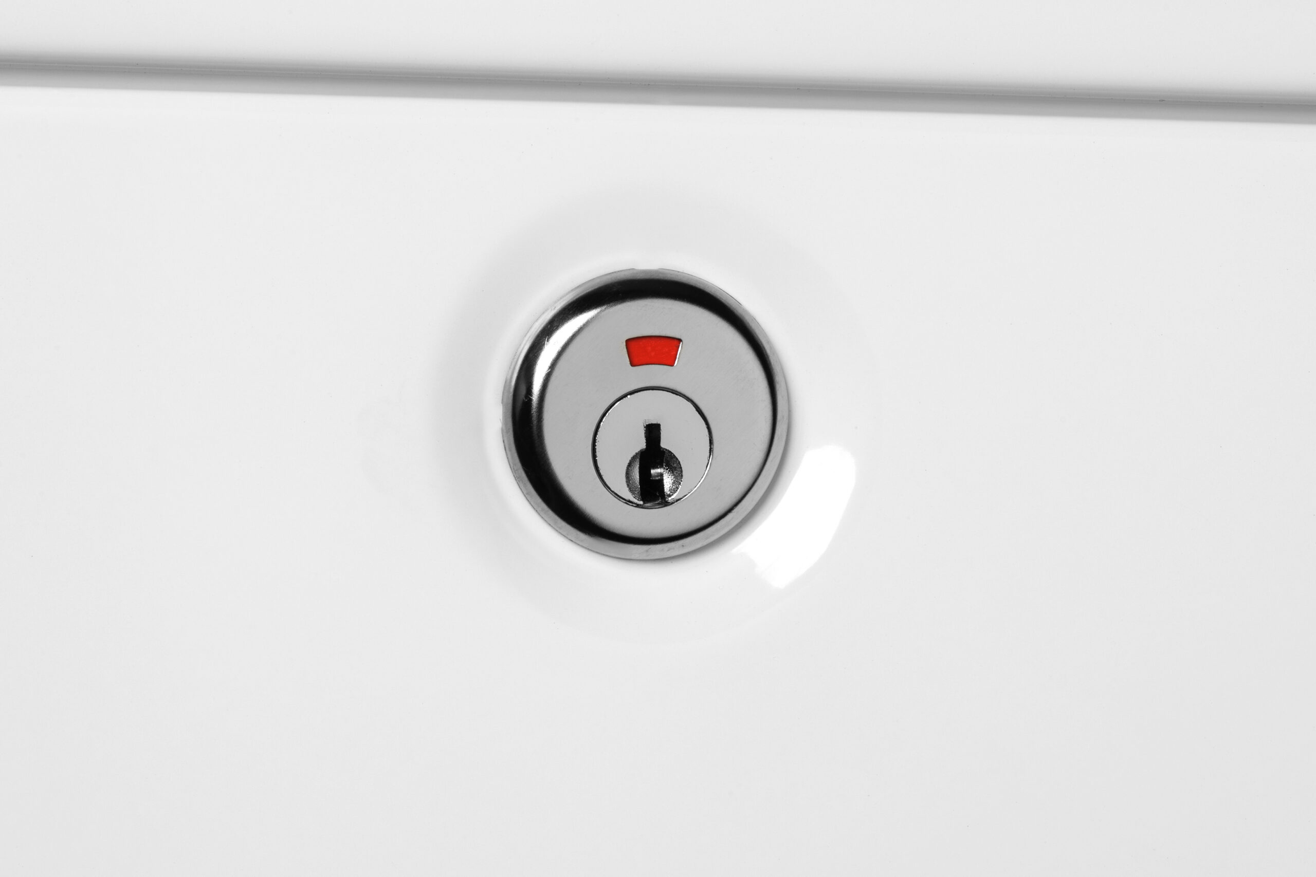Close-up of a round chrome deadbolt with a keyhole on a white door and a small red indicator above it.