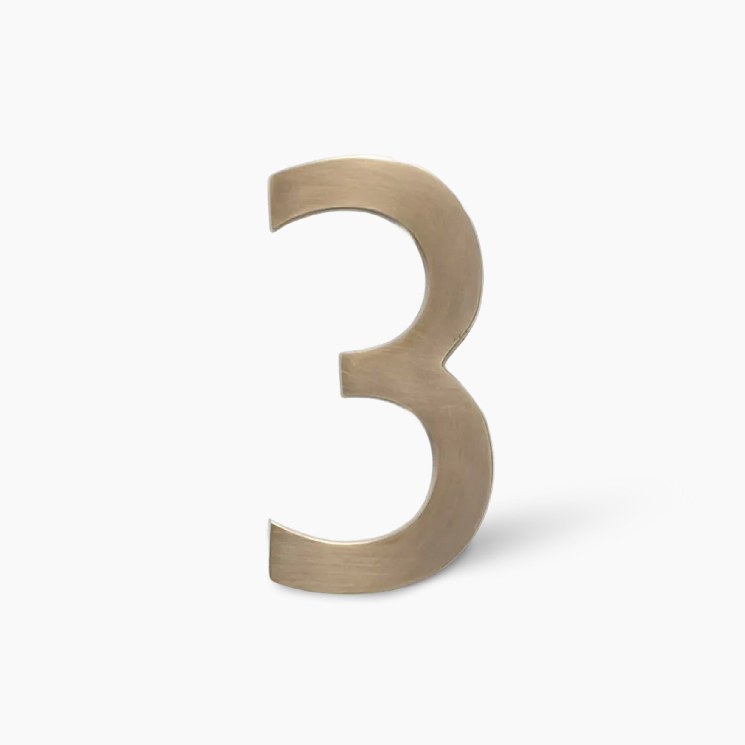 Gold-colored decorative number 3 standing upright on a white background with a soft shadow
