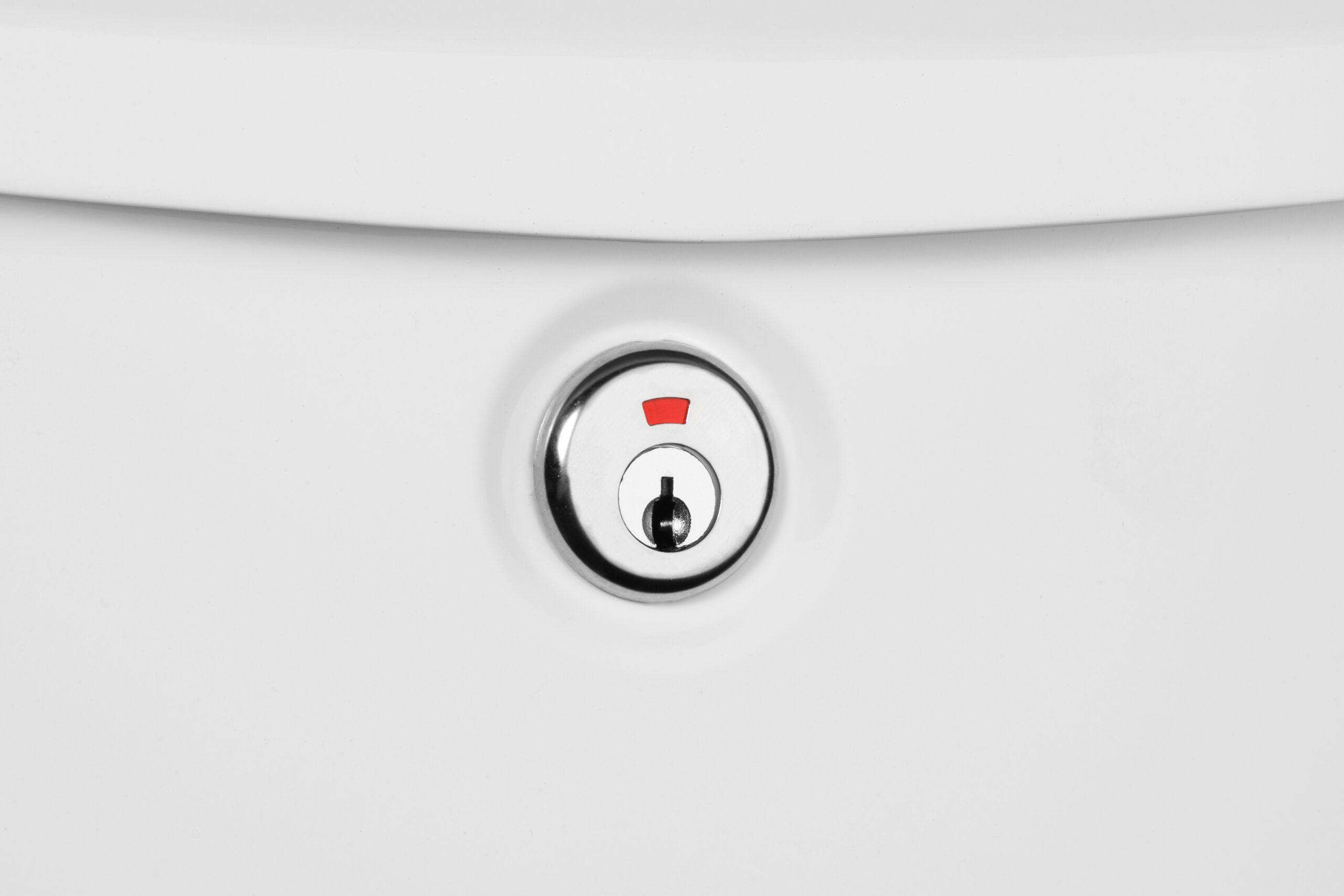 Close-up of a chrome keyhole embedded in a white surface with a small red mark above the lock.